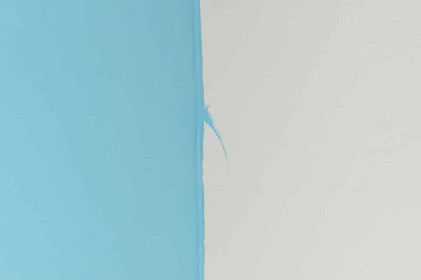 Mezza parete coperta di vernice blu con una pennellata visibile.